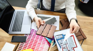 Profesyonel tamircinin yeni ev planıyla çalışmasının en iyi görüntüsü. Ofiste şık kostümlü yaratıcı bir mimar. Örnekli renkli palet. Yenileme ve iç tasarım konsepti