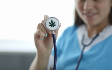 Kadın elinin steteskopla kenevir izlerine yakın plan çekilmiş hali. Doktor tıbbi malzemeler kullanıyor. Ağrı kesici. Sağlık ve tıbbi marihuana konsepti