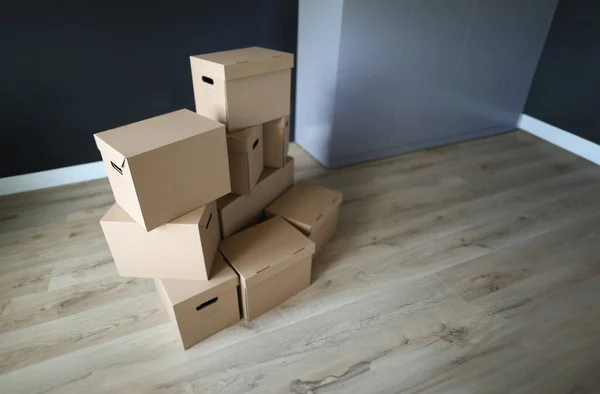 Close-up of empty carton boxes on floor. Cardboard with personal stuff. Delivery service. Stack of closed containers. Moving day and renovation in apartment concept