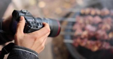 Fotoğrafçı, ızgarada şiş kebap hazırlamak için fotoğraf çeker. Blogger turist gezgini yemek çekiyor ve yemek fotoğrafçısı olarak çalışıyor
