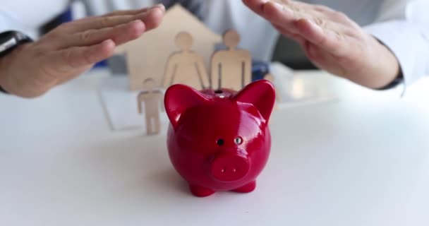 Versicherungsvertreter Schützt Sparschwein Und Familie Mit Haus Mit Händen Bauspardarlehen — Stockvideo