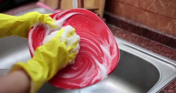 黄色の保護ゴム手袋の女性の手は赤いプレートを洗う 家庭料理の洗い方 — ストック動画