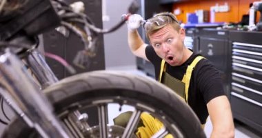 Şaşırmış bir adam motosikleti tamir ediyor ve ingiliz anahtarı filmiyle kafasını kaşıyor. Motosiklet bakım ve onarım sorunları kavramı