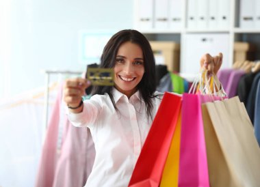 Portrait of woman holding shopping bags in store with bank credit card. Favorable shopping discounts and sales
