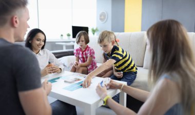 Parents and children play board game together at table. Games for whole family at home