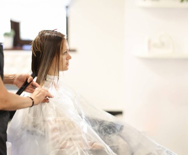 Hairdresser hands cut hair of client in beauty salon. Classic version of bob haircut technology