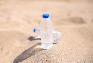 Cold drinking water in transparent bottles on sandy beach sea. Summer drinking regimen and thirst