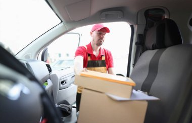 Young delivery man is loading boxes into car. Parcel delivery and logistics services