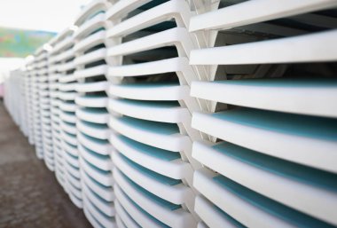 White plastic sun loungers stacked together on a sandy beach. Sun lounger rental summer sun lounger rental business