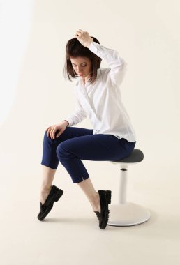 Woman in bad mood, bored and sad, sits on chair and puts hands on head. Woman in depression concept