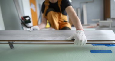Closeup of work of master on installation of flooring. Male hands working laying laminate on floor