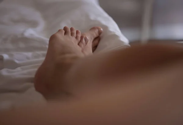 Closeup of woman feet on bed in morning. Concept of relaxation and restful sleep