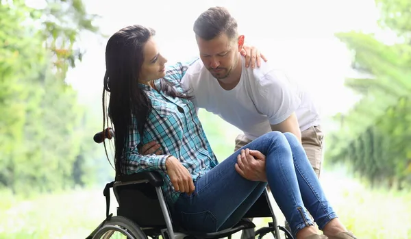 Man helps disabled woman into wheelchair. Help support and rehabilitation of the disabled
