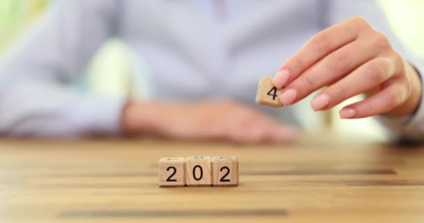 女性の手は木製の立方体から年の日付を作成するために番号4を置きます 新しい生産的な年遅い動きを開始するための自己準備の概念 — ストック動画