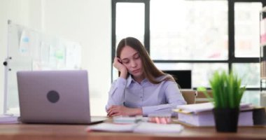 Kadın ofis çalışanı online iş görüşmesi sırasında dizüstü bilgisayarla uyuyakalıyor. Çalışan yorgun ve bitkin bir ifadeyle yavaşça gözlerini kapatır.