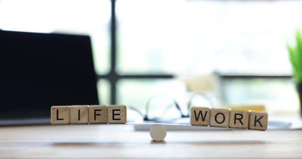オフィステーブルにスケールに置かれた木製の立方体に書かれた生命と働きのフレーズ ライフワークのバランス 個人的な生活と仕事の遅い動きを分離する利点 — ストック動画