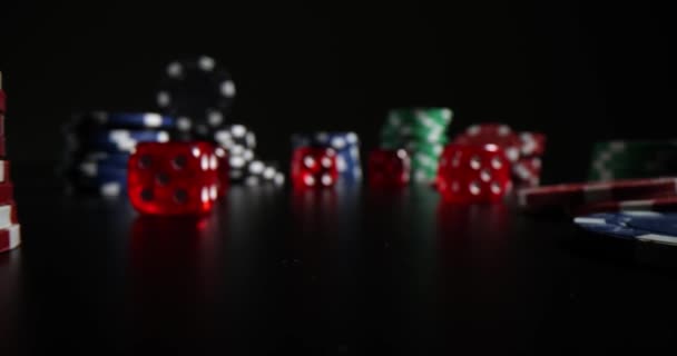 カジノチップのカラフルな束と暗い場所で黒い表面のサイコロ 違法カジノでのプロギャンブルゲームのコンセプト — ストック動画