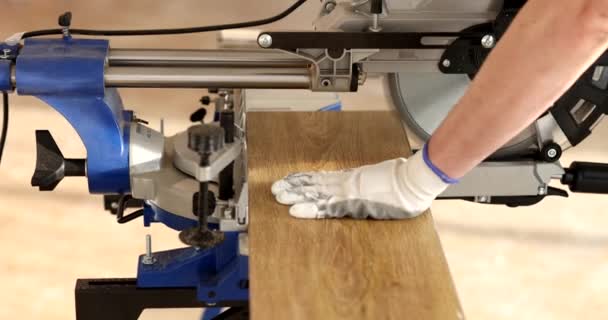 ワークショップで電気チェーンソーでパーケットボードを切断するビルダー 作業服の木製プランクをカットするハンディマン スローモーション — ストック動画