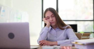 İş yerinde gözleri kapalı oturan yorgun ve genç bir stajyer öğrenci. Ofiste yorgunluk ve fazla mesai