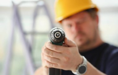 Elektrikli matkap closeup kullanarak alt kollarından. El ile iş DIY ilham geliştirme tamir dükkanı sarı kask sanayi başlangıç fikir endüstriyel eğitim meslek kariyer kavramı