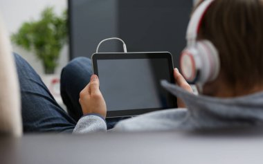 Erkek el, koltukta oturup internette sörf yaparken tablet tableti tutuyor. Müzik konseptini kapamak için uygulamayı kullanarak boş zamanların gösteriminde parmağınızı kullanın.