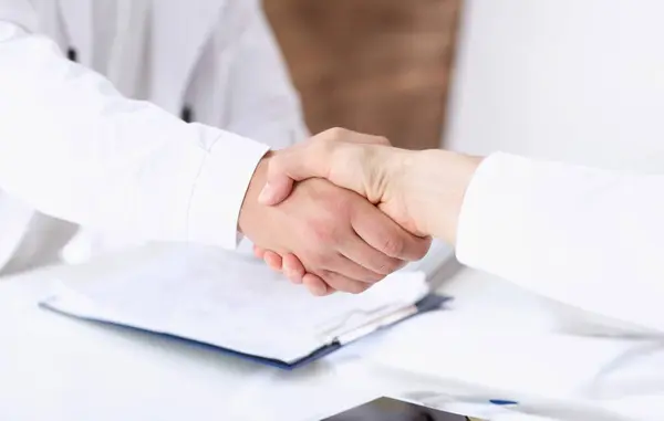 Doctor shake hand as hello with patient in office closeup. Welcoming friend introduction or thanks gesture consultation work thankful client talk team trust communication teamwork deal concept