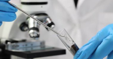 Kimyasal kaşıkla gübreyi test tüpüne döken bilim adamı kimyager. Laboratuvara yakın çekimde toprak ile birlikte ağır çekim. Toprak verimliliği kavramı artıyor