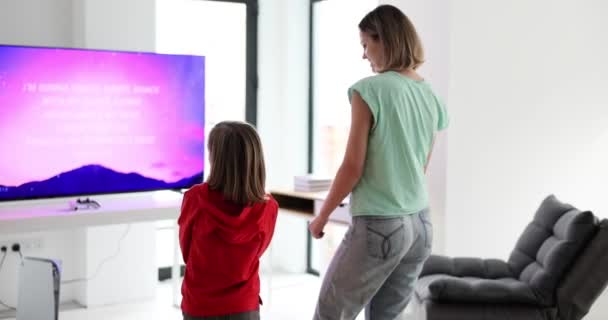 妈妈和女儿在电视机前跳舞 在家里回放4K片慢镜头 与儿童的娱乐概念 — 图库视频影像