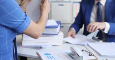 İş adamı ve kadın masada oturup zımba ve delikli yumruk filmiyle belgeleri sıralıyorlar. Kağıt işleri konsepti