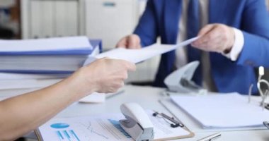 İş adamı ve kadın masada oturup zımba ve delikli yumruk filmiyle belgeleri sıralıyorlar. Kağıt işleri konsepti