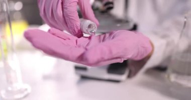 Koruyucu eldivenler giyen bir kimyager laboratuardaki 4K 'lık ağır çekimde sıvı metali elden ele döküyor. Zehirli kimyasal element kavramı