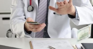 Beyaz önlüklü doktor onları dağıtırken dolarları sayıyor. En yüksek maaşlı tıp mesleği konsepti