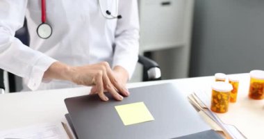 Doktor iş yerinde otururken dizüstü bilgisayarı açar. Tıbbi çalışma günü konsepti