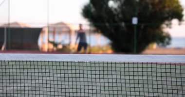 Profesyonel olarak donanımlı tenis oyuncusu ve arka plandaki tenis oyuncusu tenis topuna raketle vuruyor. Tenis oyunu
