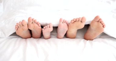Mutlu bir aile sabah ayaklarıyla uyanır. Ebeveynler ve çocuk ayakları örtülü