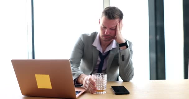 一位悲伤的商人在工作场所的笔记本电脑前喝威士忌的肖像 酗酒会导致工作中的抑郁症 — 图库视频影像