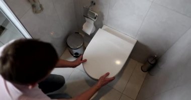 Banyoda dizlerinin üstüne çöküp tuvalete kusan bir adam. Gıda zehirlenmesi ve rotavirüs enfeksiyonu.
