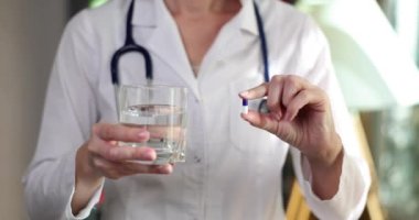 Doktorun elleri ilaç ve bir bardak su veriyor. İlaç konsepti kullanma kuralları