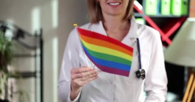 Doktor klinikte LGBT gökkuşağı bayrağı tutuyor. Ulusal sağlık sistemi konsepti LGBT gay, biseksüel ve transseksüel lezbiyenler