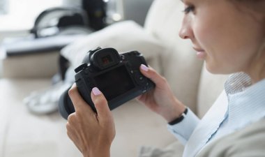 Kadın elinde siyah profesyonel kamera tutuyor. Sıfırdan nasıl profesyonel fotoğrafçı olunur