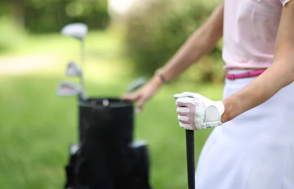Female hand of golfer in glove holds bag with golf clubs. Golf lessons concept