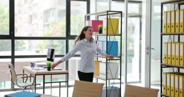 Ofiste zafer dansı yapan neşeli, genç ve çekici bir kadın. Kadın ofis çalışanı başarısını ve başarılı çalışanın zafer dansını neşeyle kutluyor.