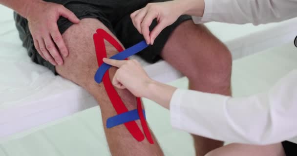 物理治疗师在人的膝盖上应用运动学粘贴 运动膝伤和治疗 — 图库视频影像