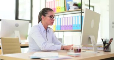 Ofisteki kadın yönetici bilgisayarda oturup monitöre bakıyor. Çalışanları uzaktan çalışma kavramı üzerine eğitmek
