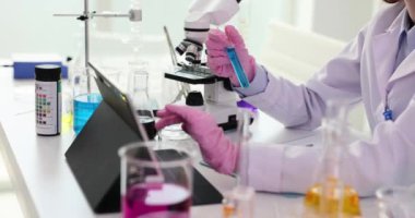 Tıbbi araştırma laboratuarı bilimcisi dijital tablet bilgisayarı kullanarak verileri analiz ediyor ve mavi sıvıyla test tüpü kullanıyor. Tıp biyolojisi ve mikrobiyolojisinin geliştirilmesi için bilimsel laboratuvar