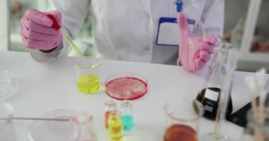 Pipetten petri şişesine kırmızı madde damlatan bilim adamının yakın çekimi. Biyokimya ve ilaç araştırmaları
