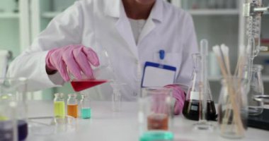Bilim adamı biyolog laboratuvarda cama kırmızı sıvı döküyor. Zehirli sıvı muayenesi