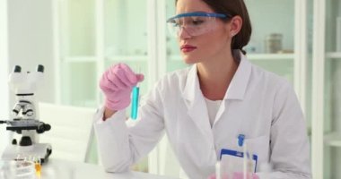 Bilim adamı deney tüpü tutuyor ve iğrenç ve iğrenç bir koku yayıyor. Biyolog nefesini tutuyor ve zehirli kokuyor.