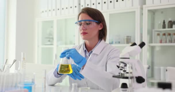 安全眼镜的化学家 美容师闻到了玻璃瓶中的黄色液体物质 并在实验室进行了实验 在实验室测试化妆品油 — 图库视频影像