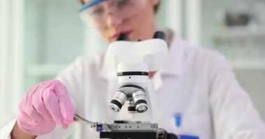 Laboratuvarda tablet ve mikroskop tutan bir bilim adamı var. İlaç araştırma ve konsept analizi